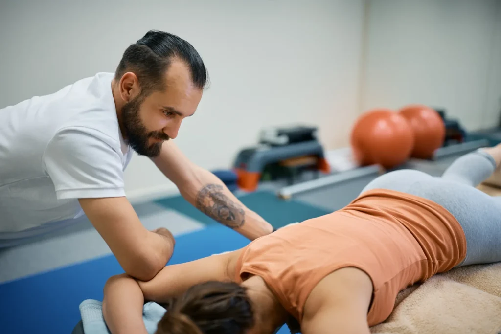 Physiotherapist performing a manual therapy session on a patient's back in a rehabilitation clinic.
