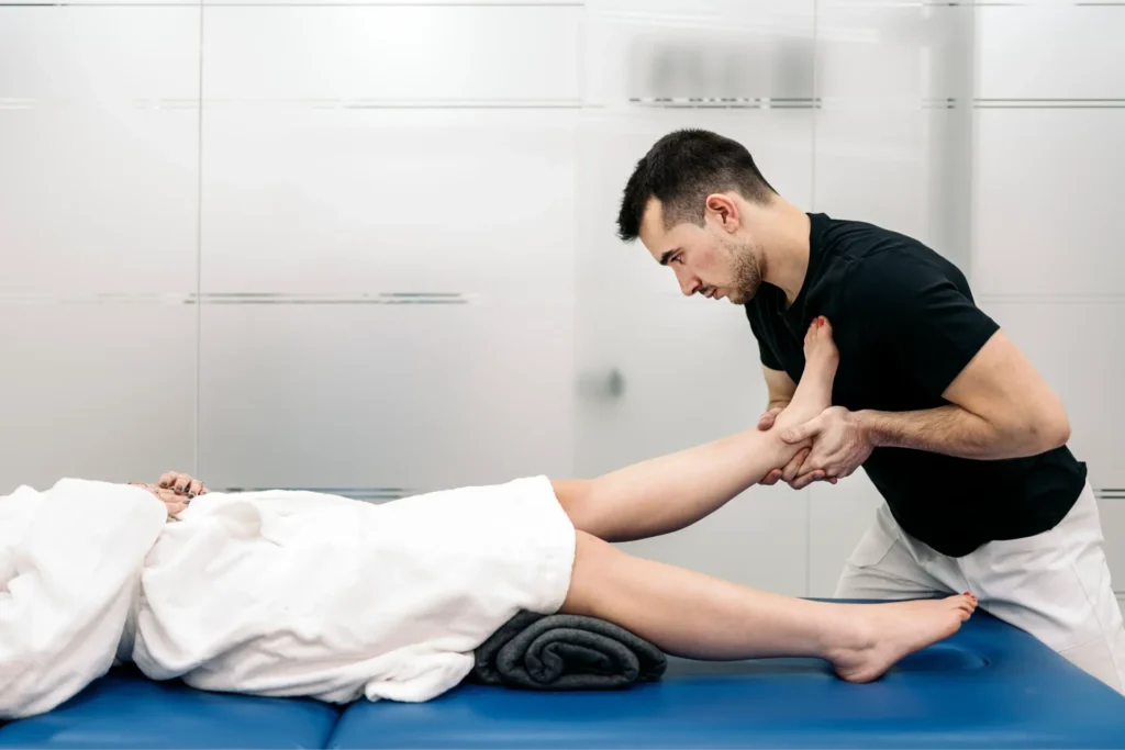 Physiotherapist performing a leg stretching technique on a patient for rehabilitation in a clinic setting.