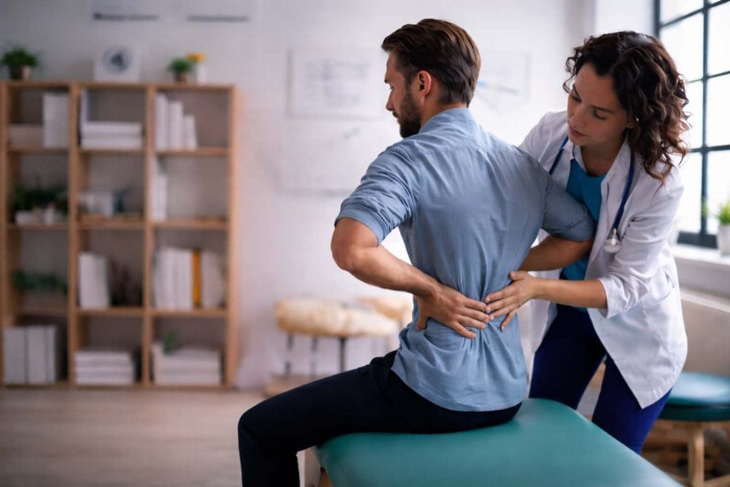 Male patient receiving sciatica treatment in Bournemouth from a female osteopath, focusing on back pain relief with expert osteopathic care.